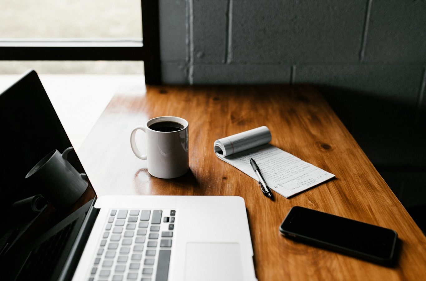 Schreibtisch Online Coaching Schreibtisch mit Laptop, Kaffeetasse, Notizblock und Smartphone.
